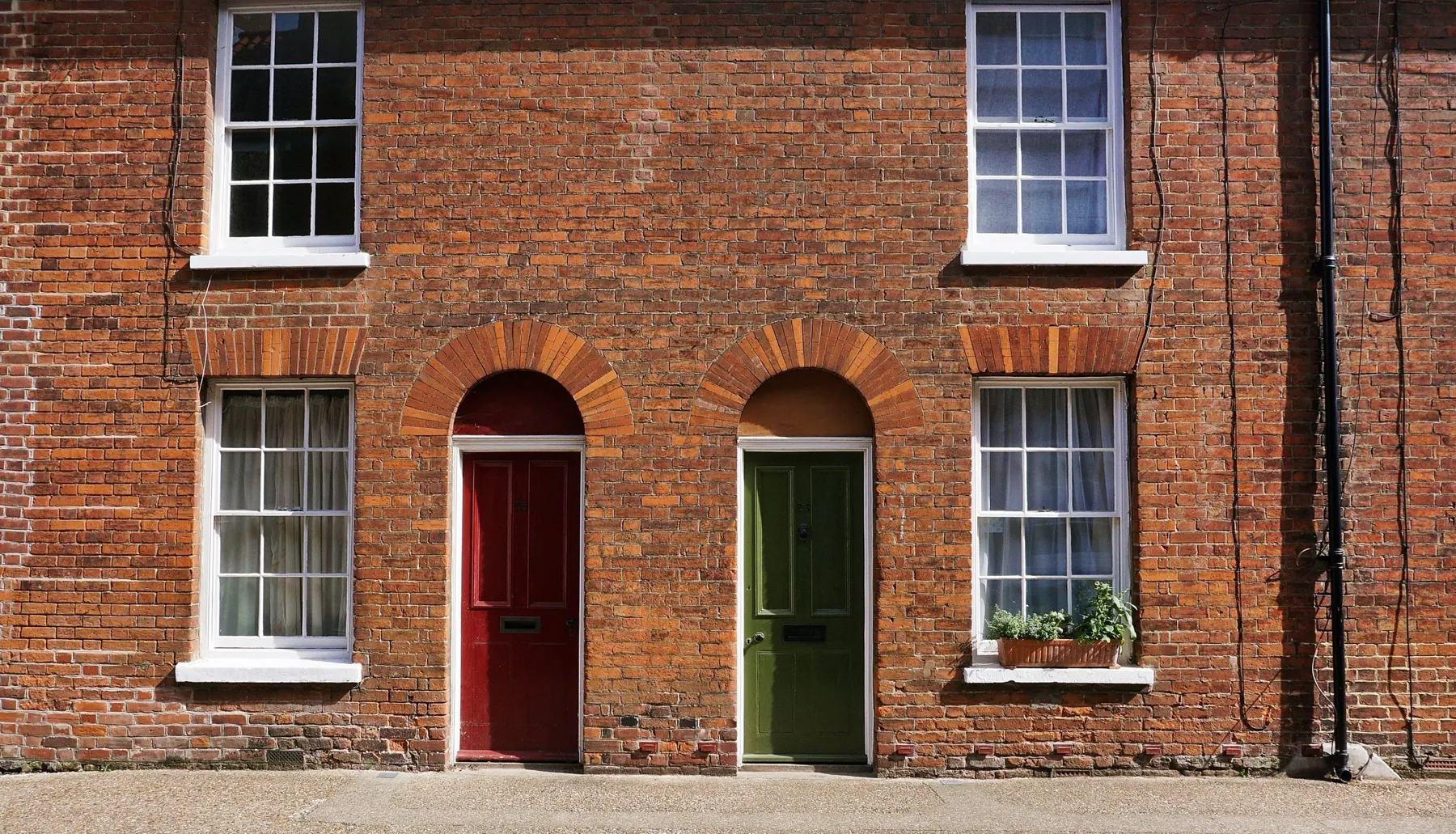 Brick terrace with white sash windows and painted front doors