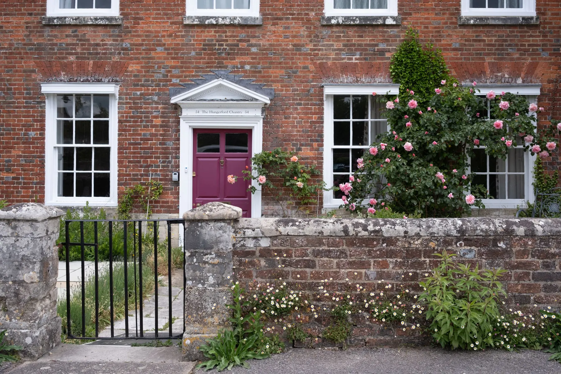Brick house with a plum front door and roses